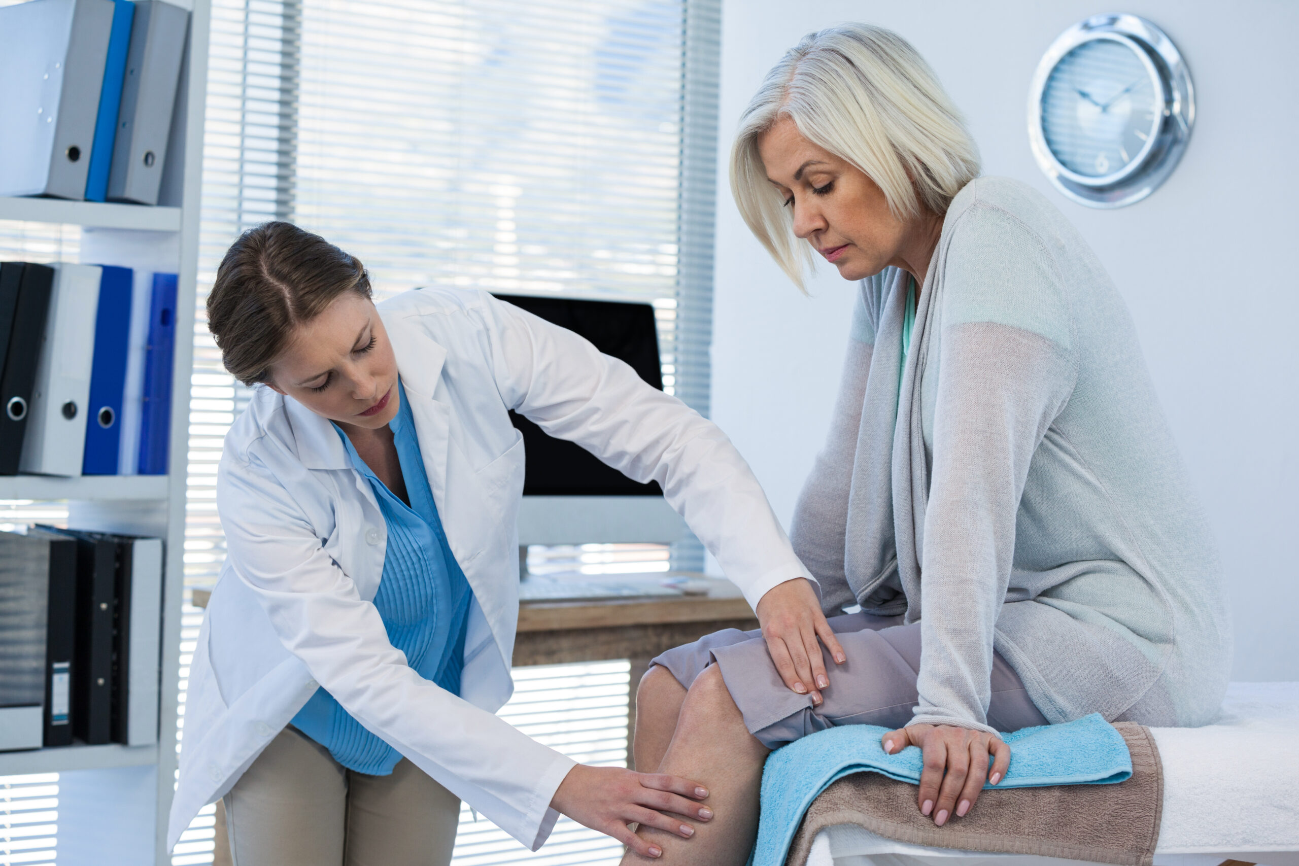 Doctor examining patient knee in clinic